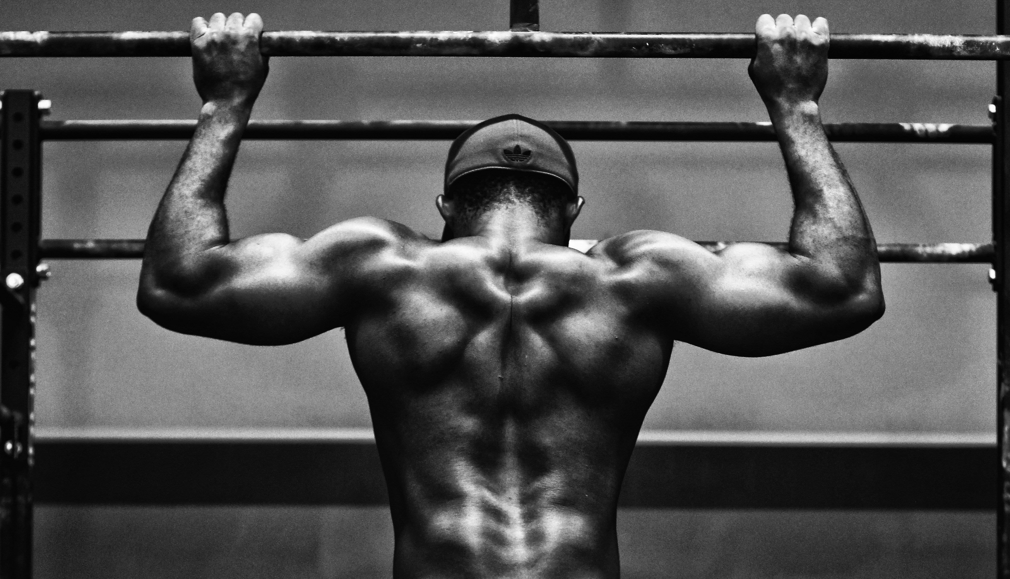 Muscular person performing pull-ups in a gym setting